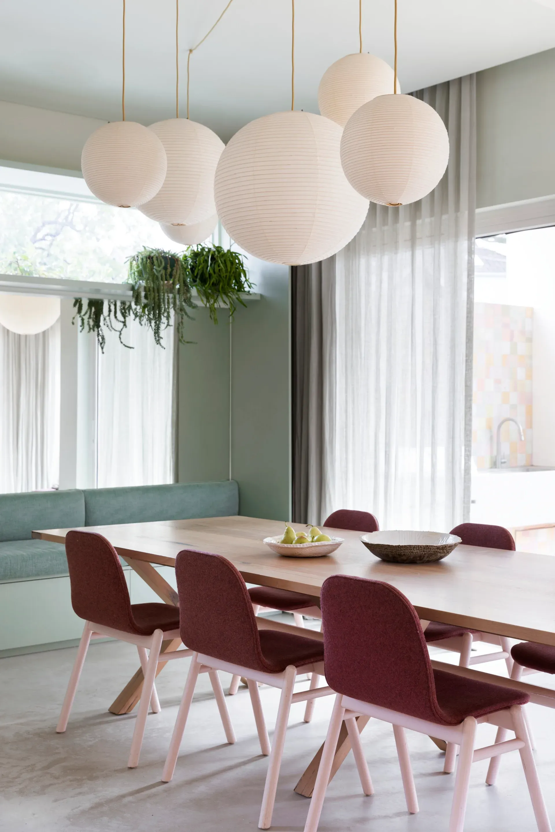 A sage and oxblood dining room over a poured concrete floor