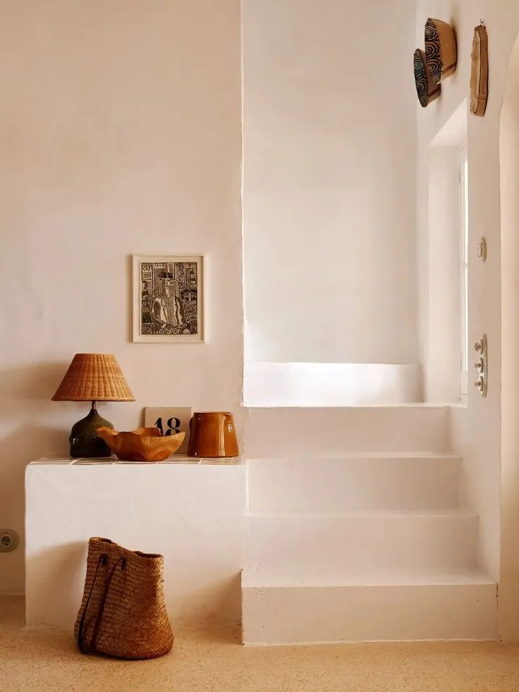 A whitewashed plaster wall, thick and hand-smoothed, glowing softly where the light crosses it.