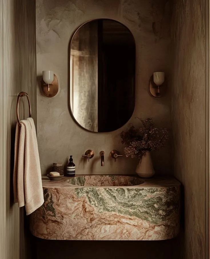 A corner of a room with soft plaster walls, a brass wall light gone warm and buttery against the chalky finish.