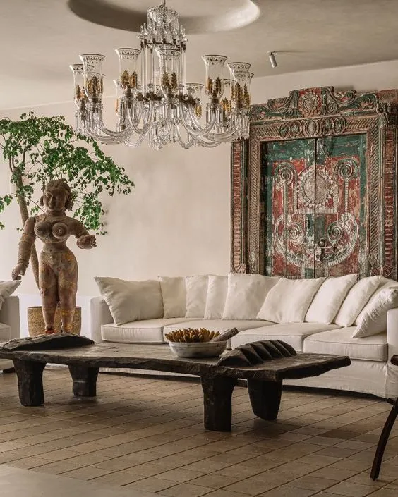 A lived-in room of travel finds and old timber pieces set against pale, cloudy plaster walls.